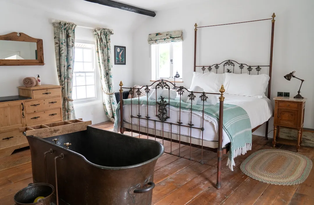 Bedroom 1 with kingsize bed, antique copper bath and sea views
